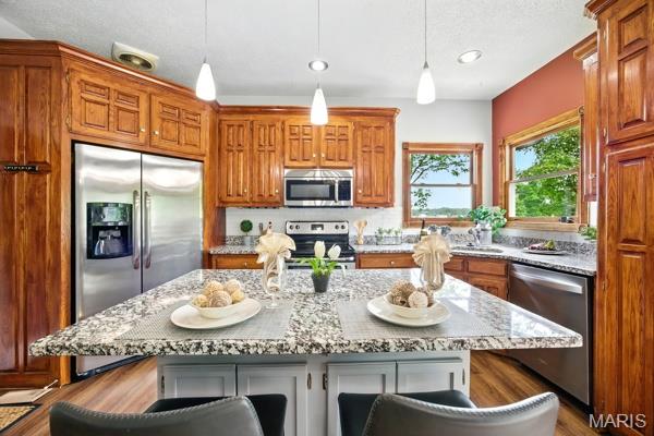 5 Sherman Ct, Hillsboro, MO 63050 - kitchen featuring stainless steel appliances, brown cabinets, a kitchen bar, light stone countertops, and recessed lighting