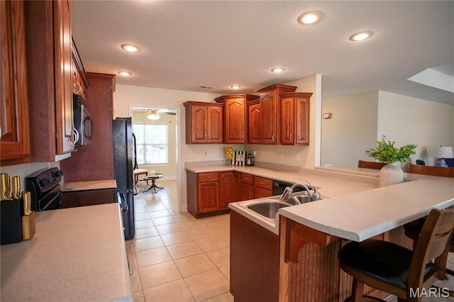 1106 Tulip Trce, Sikeston, MO 63801 - kitchen with a kitchen breakfast bar, a peninsula, black appliances, light countertops, and light tile patterned flooring