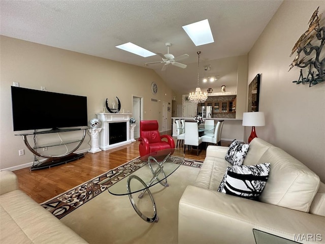 17 Battersea Ct Unit 6B, Ofallon, MO 63366 - living room featuring a skylight, wood finished floors, vaulted ceiling, a chandelier, and ceiling fan