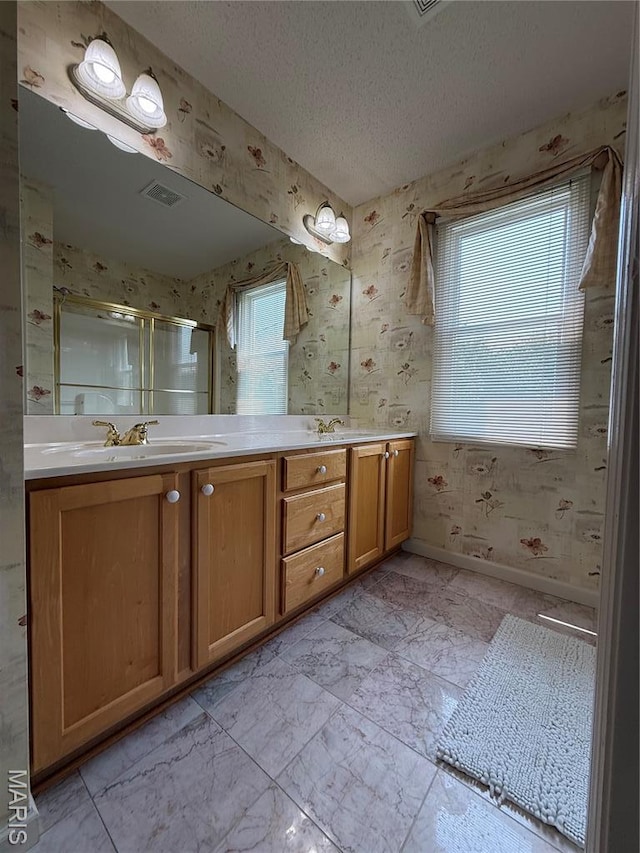 17 Battersea Ct Unit 6B, Ofallon, MO 63366 - bathroom with wallpapered walls, double vanity, a stall shower, and a textured ceiling