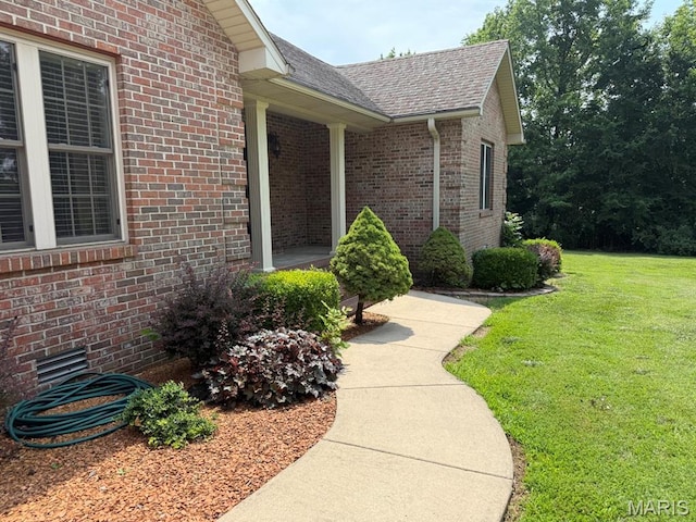 17138 E Cedar Hills Dr, Dexter, MO 63841 - view of exterior entry featuring a yard, roof with shingles, and brick siding