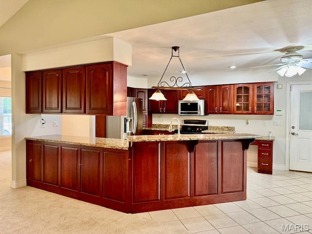 17138 E Cedar Hills Dr, Dexter, MO 63841 - kitchen featuring stainless steel appliances, reddish brown cabinets, a peninsula, light stone counters, and a ceiling fan