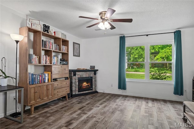1939 Grandview Dr, Cape Girardeau, MO 63701 - living area featuring dark wood finished floors, a ceiling fan, a stone fireplace, and a textured ceiling
