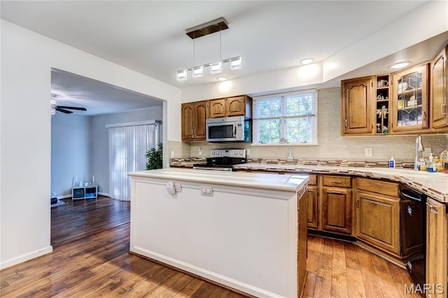 67 Kings Dr, Florissant, MO 63034 - kitchen with stainless steel appliances, light countertops, tasteful backsplash, and brown cabinets