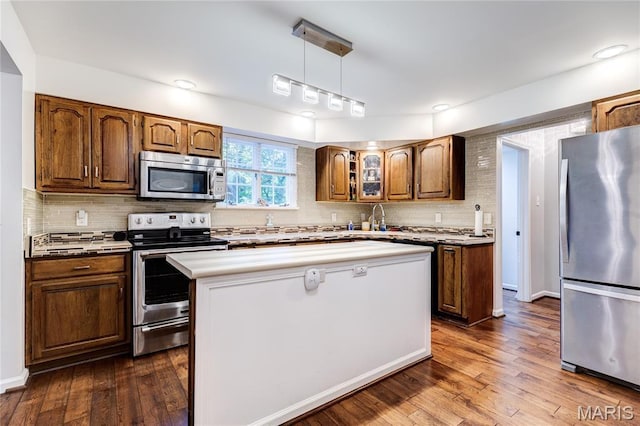 67 Kings Dr, Florissant, MO 63034 - kitchen with appliances with stainless steel finishes, backsplash, a center island, and dark wood-style flooring