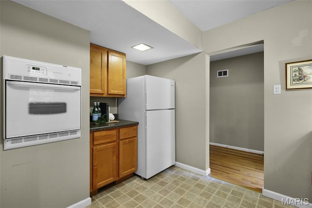 450 Forest Green Dr, Webster Groves, MO 63119 - kitchen with white appliances, brown cabinetry, dark countertops, and light floors