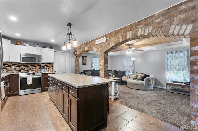 115 Whitener St, Marquand, MO 63655 - kitchen with appliances with stainless steel finishes, arched walkways, light colored carpet, white cabinets, and dark brown cabinetry