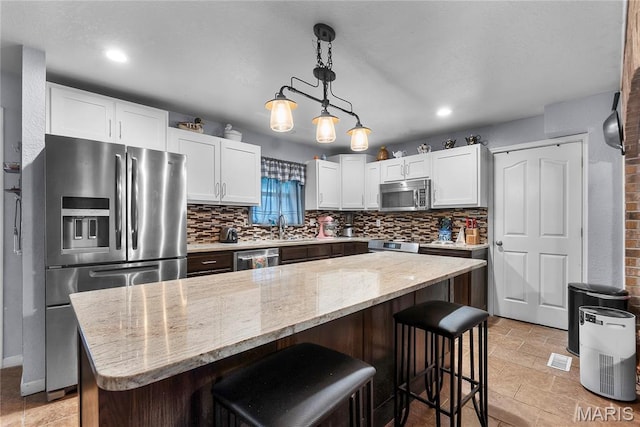 115 Whitener St, Marquand, MO 63655 - kitchen featuring stainless steel appliances, backsplash, light stone counters, white cabinets, and a breakfast bar area