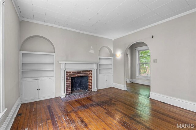 325 N Lorimier St, Cape Girardeau, MO 63701 - unfurnished living room with built in shelves, hardwood / wood-style floors, arched walkways, crown molding, and a brick fireplace