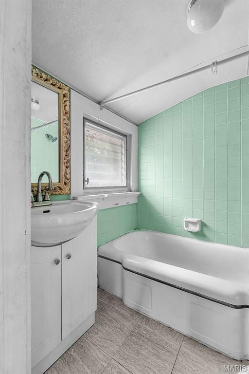 325 N Lorimier St, Cape Girardeau, MO 63701 - full bathroom featuring vanity, a bath, lofted ceiling, tile walls, and a textured ceiling