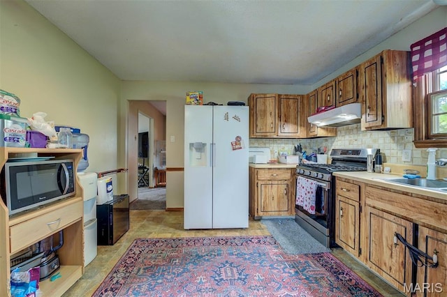 6048 La Chateau Ct, Saint Louis, MO 63129 - kitchen with stainless steel appliances, under cabinet range hood, brown cabinets, decorative backsplash, and light countertops