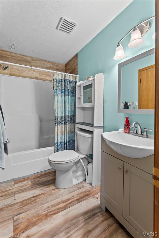 1802 Old Cape Rd, Jackson, MO 63755 - full bathroom with wood finished floors, vanity, shower / bathtub combination with curtain, and a textured ceiling