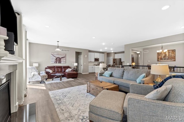 2333 Cabric Dr, Saint Charles, MO 63301 - living room featuring light wood-type flooring, a chandelier, a high end fireplace, and recessed lighting