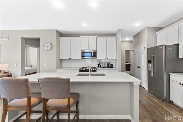 2333 Cabric Dr, Saint Charles, MO 63301 - kitchen with stainless steel appliances, dark wood-style flooring, backsplash, white cabinets, and light countertops