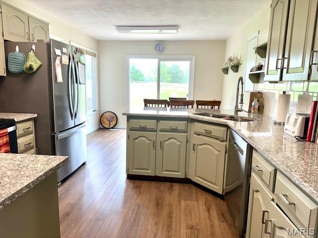 256 Black Oak Trl, Jackson, MO 63755 - kitchen with stainless steel appliances, a peninsula, dark wood-style flooring, and light stone countertops