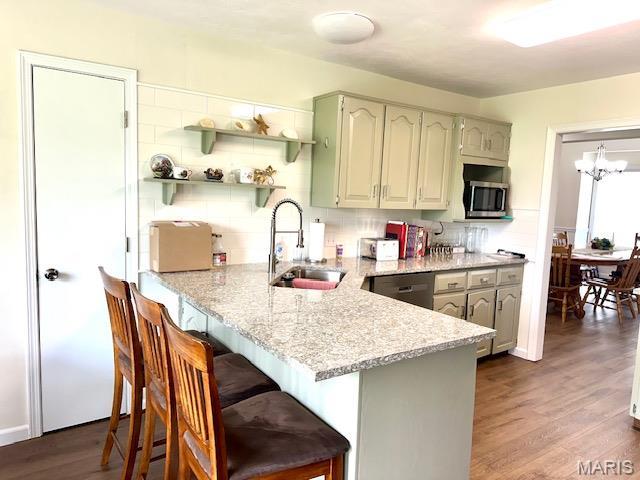256 Black Oak Trl, Jackson, MO 63755 - kitchen featuring stainless steel appliances, a peninsula, a breakfast bar area, dark wood-style floors, and light stone counters