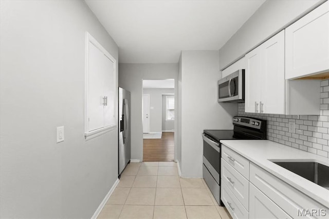 209 Monica Dr, Saint Louis, MO 63127 - kitchen with stainless steel appliances, tasteful backsplash, white cabinetry, light countertops, and light tile patterned flooring