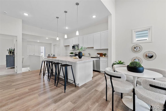 114 Marais Temps Clair, Saint Charles, MO 63301 - kitchen featuring a kitchen bar, light wood-style flooring, appliances with stainless steel finishes, white cabinets, and hanging light fixtures