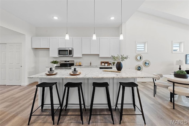 114 Marais Temps Clair, Saint Charles, MO 63301 - kitchen featuring appliances with stainless steel finishes, a kitchen bar, white cabinets, light wood-style floors, and recessed lighting