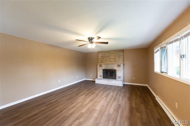 21 Mcfarland Dr, Rolla, MO 65401 - unfurnished living room featuring baseboard heating, ceiling fan, a brick fireplace, and dark wood-style floors