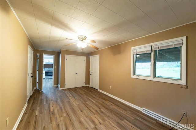 21 Mcfarland Dr, Rolla, MO 65401 - unfurnished bedroom featuring baseboard heating, wood finished floors, ornamental molding, and ceiling fan