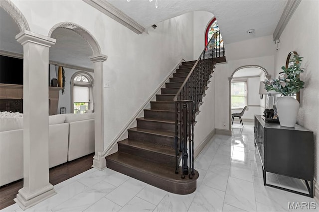 1259 Hampton Park Dr, Richmond Heights, MO 63117 - staircase featuring ornate columns, marble look tiles, a textured ceiling, arched walkways, and crown molding