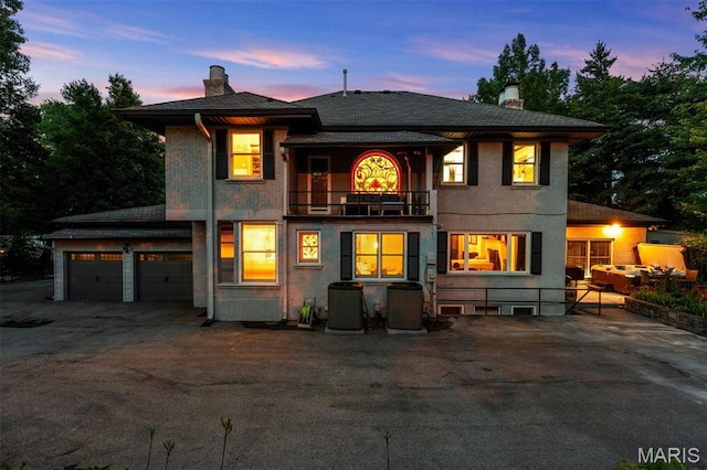 1259 Hampton Park Dr, Richmond Heights, MO 63117 - back of property at dusk featuring a balcony, a chimney, asphalt driveway, and an attached garage