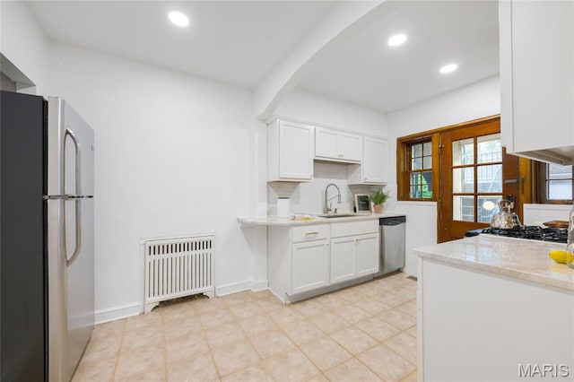 8100 Delmar Blvd Unit 1W, University City, MO 63130 - kitchen featuring freestanding refrigerator, radiator heating unit, stainless steel dishwasher, white cabinetry, and decorative backsplash