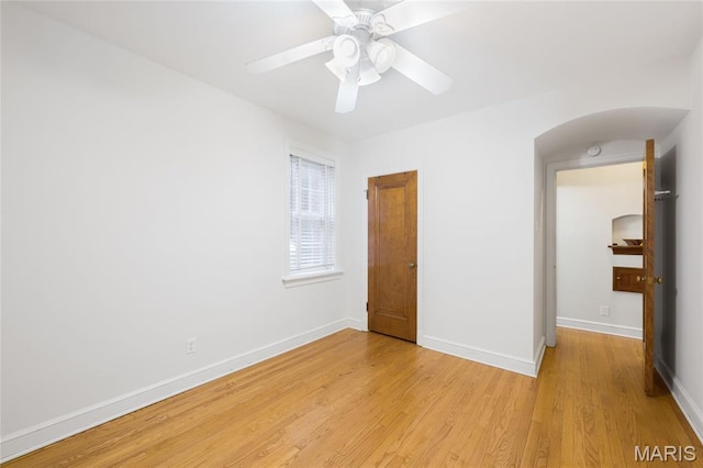 8100 Delmar Blvd Unit 1W, University City, MO 63130 - unfurnished bedroom featuring arched walkways, light wood-style floors, and a ceiling fan