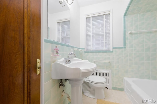 8100 Delmar Blvd Unit 1W, University City, MO 63130 - bathroom with tile walls, tile patterned floors, radiator, a bathtub, and wainscoting