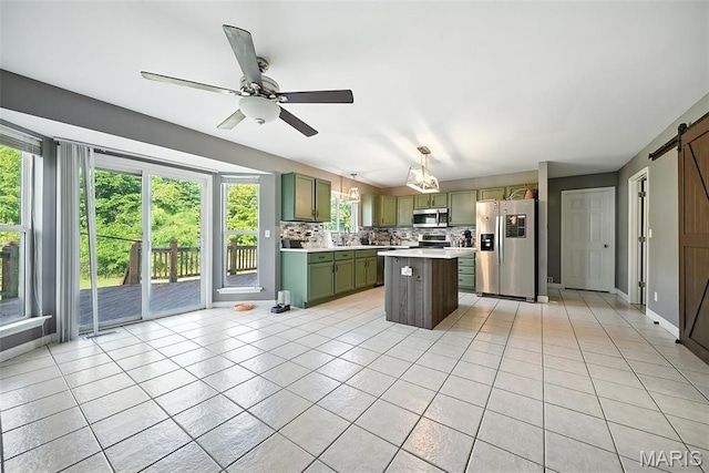 11264 Village Dr, Foristell, MO 63348 - kitchen with stainless steel appliances, a barn door, green cabinets, light countertops, and light tile patterned floors