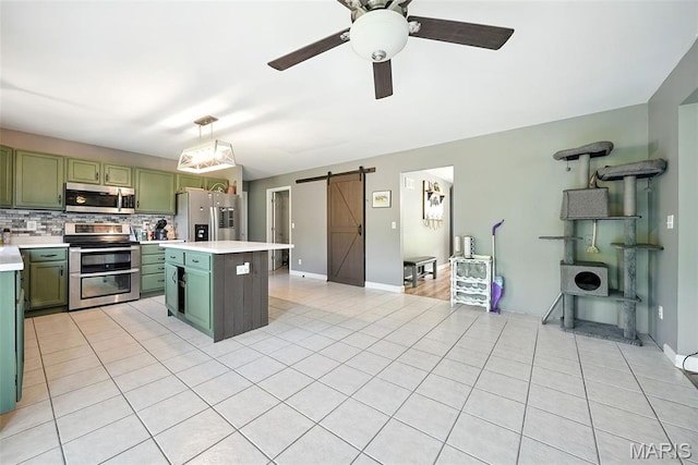 11264 Village Dr, Foristell, MO 63348 - kitchen featuring green cabinetry, stainless steel appliances, a barn door, light countertops, and backsplash