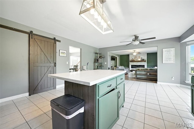 11264 Village Dr, Foristell, MO 63348 - kitchen featuring light tile patterned floors, ceiling fan, light countertops, a barn door, and a center island