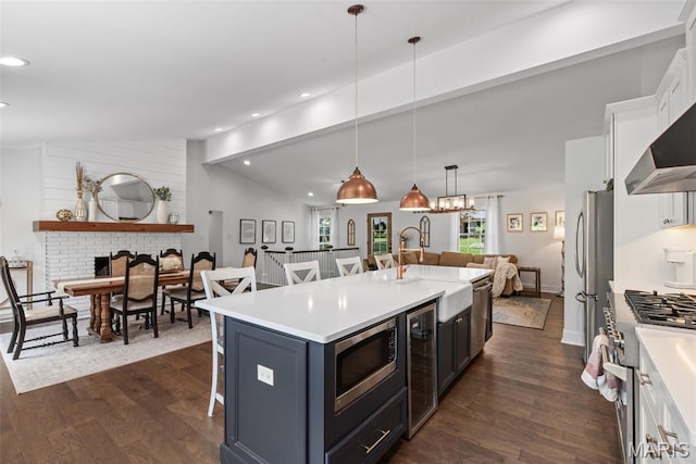 1715 Pine Hill Dr, Des Peres, MO 63131 - kitchen featuring stainless steel appliances, open floor plan, dark wood-style floors, a breakfast bar area, and plenty of natural light