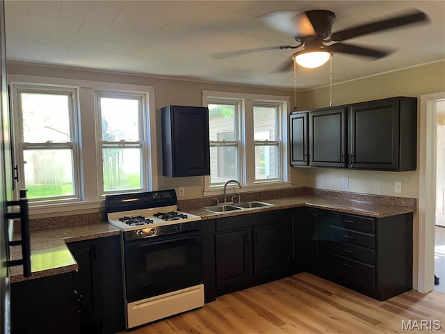 1032 W Pearl St, Staunton, IL 62088 - kitchen with range with gas cooktop, light wood-type flooring, a ceiling fan, dark countertops, and dark cabinets