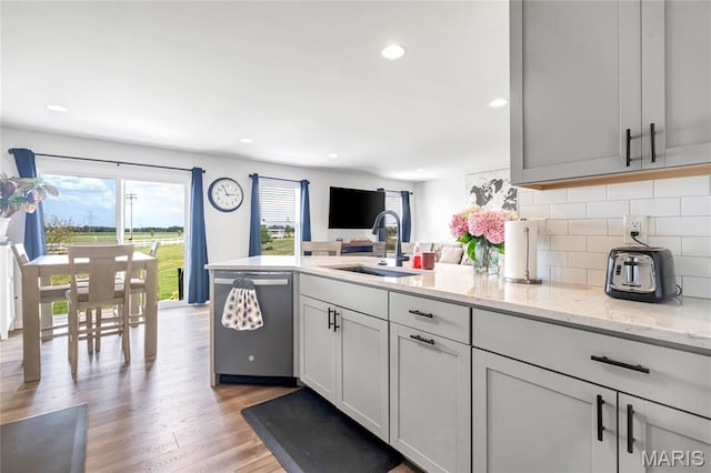 130 Baycrest Ct, Saint Charles, MO 63301 - kitchen with dishwasher, a peninsula, backsplash, light wood-style flooring, and light stone counters