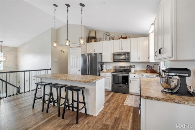 1424 Cortez Dr, Hillsboro, MO 63050 - kitchen with appliances with stainless steel finishes, a center island, wood finished floors, white cabinetry, and a breakfast bar