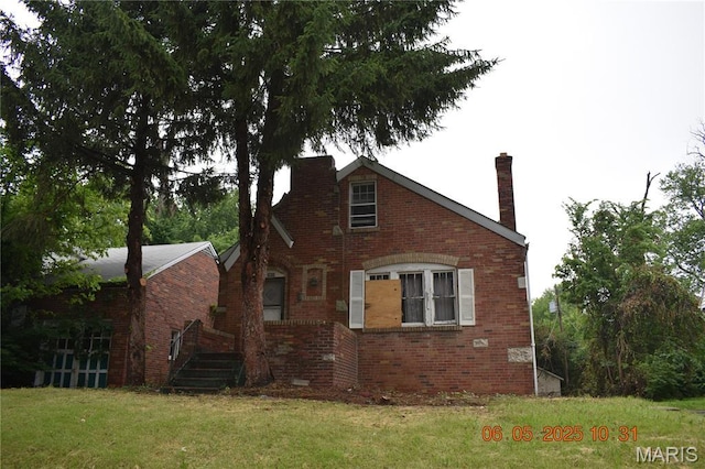 3835 Oakridge Blvd, Northwoods, MO 63121 - view of side of home featuring a chimney, brick siding, and a lawn