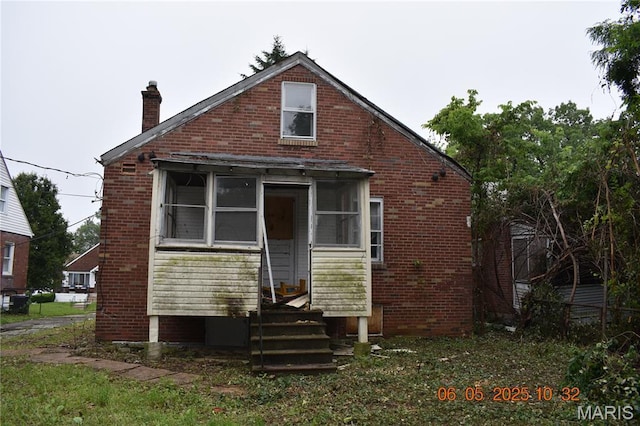 3835 Oakridge Blvd, Northwoods, MO 63121 - rear view of property with a chimney, brick siding, and a sunroom