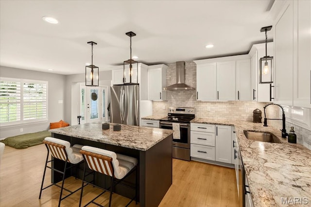 6521 Woodland Dr, Cedar Hill, MO 63016 - kitchen featuring stainless steel appliances, wall chimney range hood, light wood-style flooring, a breakfast bar, and a kitchen island