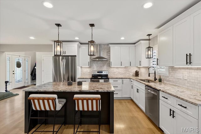 6521 Woodland Dr, Cedar Hill, MO 63016 - kitchen featuring stainless steel appliances, wall chimney range hood, a kitchen island, a breakfast bar, and white cabinets
