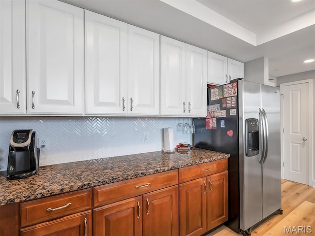 314 N Broadway Unit 1107, Saint Louis, MO 63102 - kitchen with stainless steel fridge, dark stone counters, tasteful backsplash, white cabinets, and light wood-style flooring