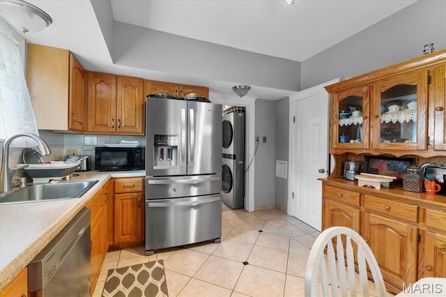 5140 Christy Ave, Saint Louis, MO 63116 - kitchen featuring appliances with stainless steel finishes, estacked washer and dryer, decorative backsplash, and brown cabinetry