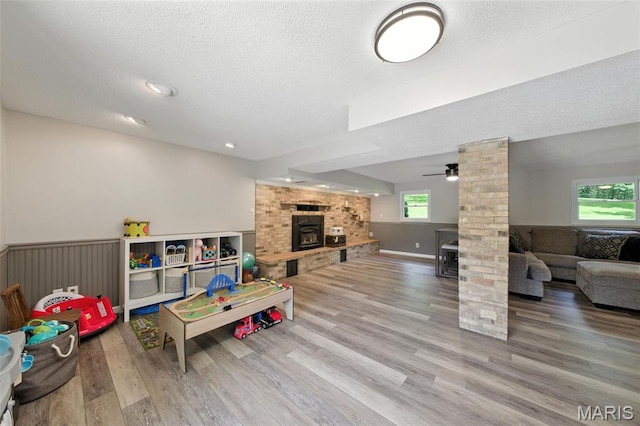 4472 Liberty Ridge Rd, De Soto, MO 63020 - playroom featuring wood finished floors, ceiling fan, a textured ceiling, a brick fireplace, and ornate columns