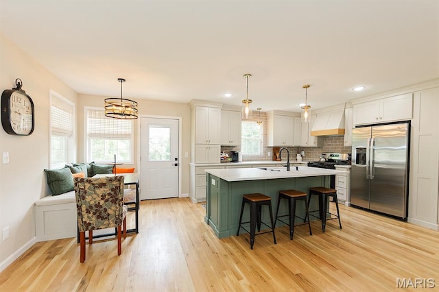 300 E 11th St, Salem, MO 65560 - kitchen with appliances with stainless steel finishes, light wood-style floors, custom range hood, light countertops, and a breakfast bar