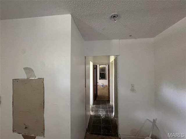 hall with tile patterned floors and a textured ceiling