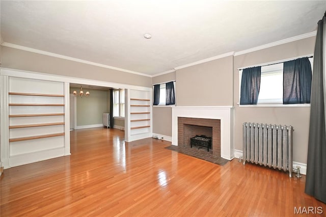 5322 Lansdowne Ave, Saint Louis, MO 63109 - unfurnished living room featuring radiator, wood finished floors, a chandelier, a fireplace, and crown molding