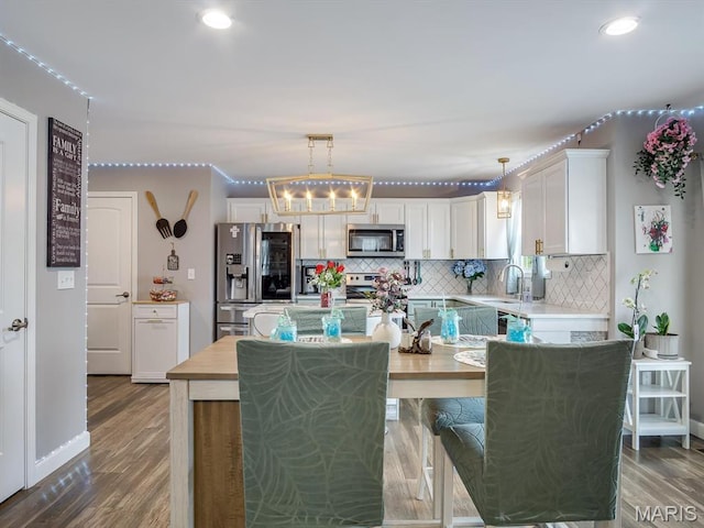 1050 Creekside Dr, Waterloo, IL 62298 - kitchen with appliances with stainless steel finishes, white cabinetry, light countertops, tasteful backsplash, and wood finished floors