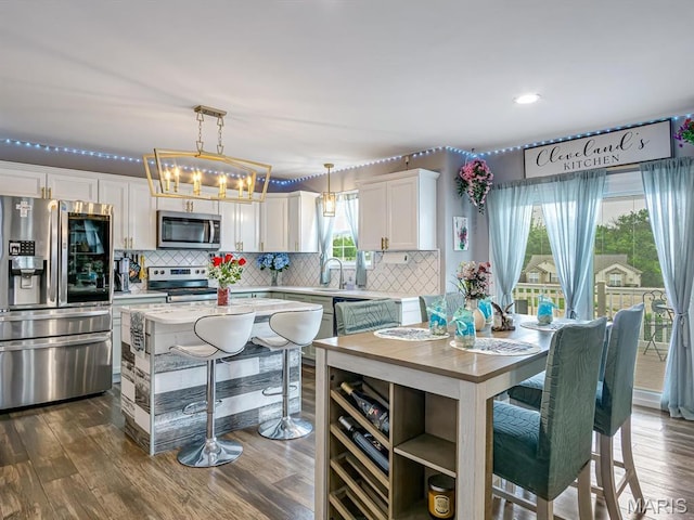 1050 Creekside Dr, Waterloo, IL 62298 - kitchen featuring appliances with stainless steel finishes, light countertops, white cabinetry, backsplash, and pendant lighting