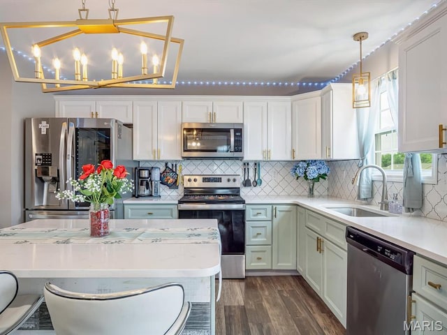 1050 Creekside Dr, Waterloo, IL 62298 - kitchen featuring appliances with stainless steel finishes, light countertops, hanging light fixtures, dark wood-type flooring, and decorative backsplash
